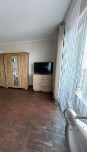 - un salon avec une télévision et une grande fenêtre dans l'établissement Apartament CALMA I, à Krynica Morska
