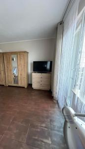 a living room with a tv and a large window at Apartament CALMA I in Krynica Morska