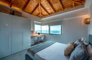 a bedroom with a bed and a desk with windows at Lithos Retreat 1 in Káto Sélitsa