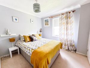 a bedroom with a bed with a yellow blanket at Beautiful apartment in Guildford with parking in Send