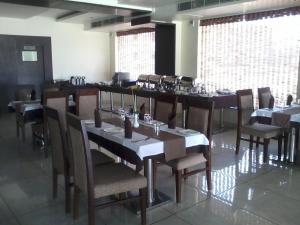 jadalnia ze stołami i krzesłami w restauracji w obiekcie Pipul Utkal Continental w mieście Jhārsuguda