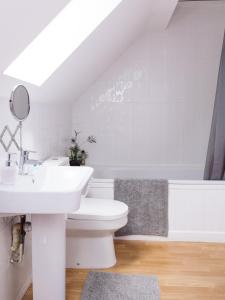uma casa de banho branca com um lavatório e um WC em Beautiful apartment in Guildford with parking em Send