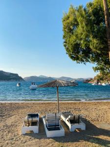 2 ligstoelen en een parasol op het strand bij Agnanti Beach House in Patmos