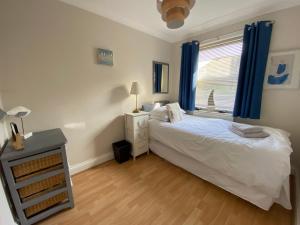 a bedroom with a bed and a window with blue curtains at Harbour Mews Central Location Near Beach in Whitstable