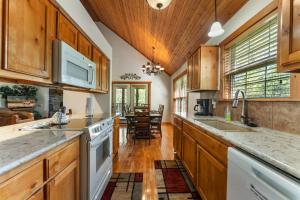 una cocina con armarios de madera y electrodomésticos blancos en Whispering Woods Lodge Home, en Branson West