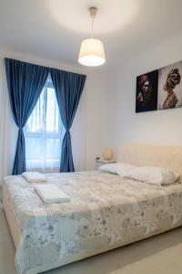 a bedroom with a bed with blue curtains and a window at GviTown Central Apartment in Bucharest