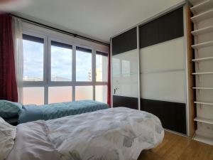 um quarto com uma cama e uma grande janela em Spacious Apartment near Paris, for Family and Friends em Montrouge