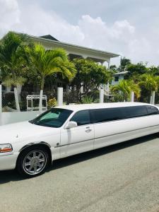 una limousine bianca parcheggiata di fronte a una casa. di HCEAS villa is 5 min fr. airport & to the beaches a Bon Accord