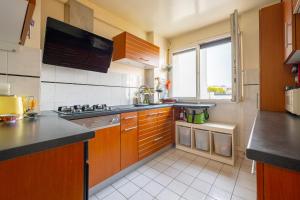 uma cozinha com armários de madeira e uma grande janela em Spacious Apartment near Paris, for Family and Friends em Montrouge
