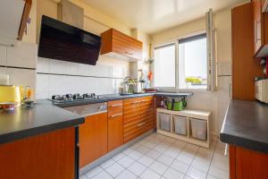 a kitchen with wooden cabinets and a large window at Spacious and comfortable apartment - Perfect for families & friends - near public transportation in Montrouge