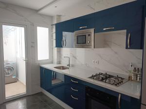 eine Küche mit blauen Schränken, einer Spüle und einer Mikrowelle in der Unterkunft The Oxygen 9 in Tétouan