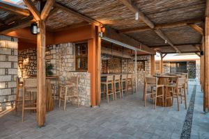 a patio with a bar with wooden chairs and tables at Trinity Design Suites in Valanidorachi