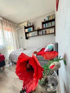 un soggiorno con un fiore rosso in un vaso di Апартамент във вила Артемида a Varna