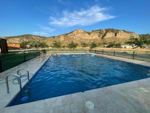 a pool with people in it with mountains in the background at Granja escuela con Bungalows in San Martín de la Vega