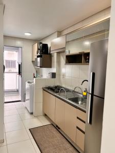 a kitchen with a sink and a refrigerator at Apto amplo e confortável in Tijucas