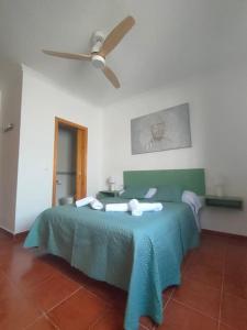 1 dormitorio con 1 cama verde y ventilador de techo en Ventana al Albarracin, en Benamahoma
