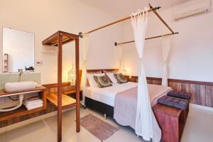 1 dormitorio con cama con dosel y espejo en Pousada Ubatuba Flats, en Ubatuba