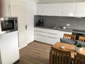 uma cozinha com armários brancos e uma mesa com cadeiras em Ferienhaus Kader em Eckernförde