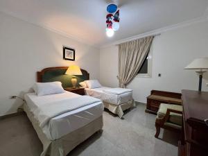 1 dormitorio con 2 camas, escritorio y ventana en شقه مفروشه فندقيه الترا مودرن فيو رائع لاصحاب الرقي والتمييز, en El Cairo