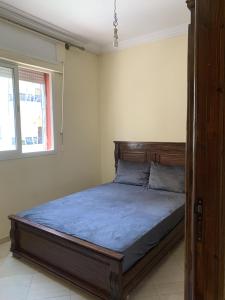 - une chambre avec un lit doté d'une tête de lit en bois et d'une fenêtre dans l'établissement kafam, à Meknès