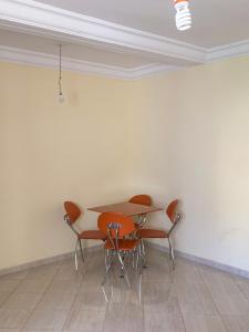 une table et des chaises dans une pièce dotée d'un mur blanc dans l'établissement kafam, à Meknès