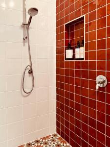 a bathroom with a shower with red and white tiles at The Anchorage- A waterfront 70’s retreat in Dora Creek