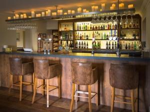 a bar with three bar stools and bottles of alcohol at Derby Arms in Longridge