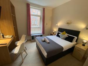 1 dormitorio con cama, escritorio y ventana en Green Gables Hotel, en Scarborough