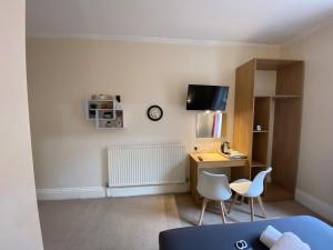 a room with a desk with two chairs and a tv at Green Gables Hotel in Scarborough