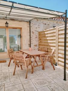 a wooden table and chairs on a patio at Les Granges des Petits Couleurs in Les Épesses