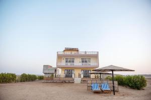 sunshine villa في سفاجا: كرسيان بلو وبيضاء ومظلة على شاطئ