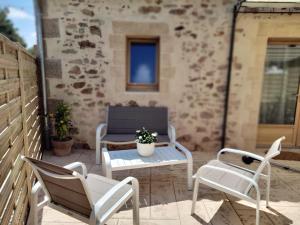 a patio with white chairs and a table and a bench at Les Granges des Petits Couleurs in Les Épesses