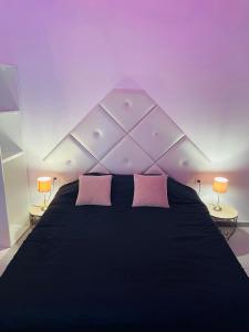 1 dormitorio con cama negra y almohadas rosas en jolie maison individuelle 50 m2 ,design et climatisée, tout confort, wifi, terasse privée , 5 min plage et autoroute, stationnement gratuit en Marsella