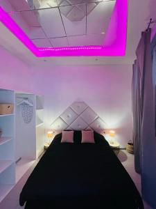 a bedroom with a black bed with pink lighting at jolie maison individuelle 50 m2 ,design et climatisée, tout confort, wifi, terasse privée , 5 min plage et autoroute, stationnement gratuit in Marseille
