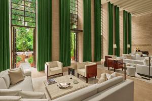 uma sala de estar com mobiliário branco e paredes verdes em The Rome EDITION em Roma