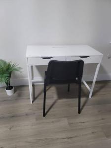 a white desk with a black chair and a plant at Docker in Timberlea