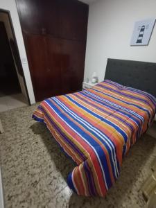 a bed with a colorful striped blanket on the floor at Depto 4-6 Personas in San Juan