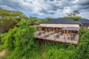 uma vista aérea de um edifício com mesas e cadeiras num deque em JW Marriott Masai Mara Lodge em Masai Mara