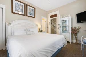 a bedroom with a white bed and a tv at Historic Branson Hotel - Quiet Quilt Room with King Bed - Downtown - FREE TICKETS INCLUDED in Branson