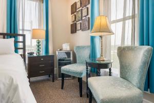 a bedroom with two chairs and a table with a lamp at Historic Branson Hotel - Serendipity Room with Queen Bed - Downtown - FREE TICKETS INCLUDED in Branson