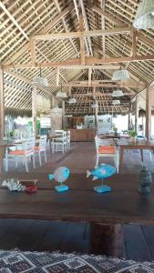 Habitación con mesas, sillas y banco de madera. en Rua Beach Resort Sumba en Rua