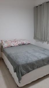 ein Bett mit einer grauen Decke und einem Fenster in der Unterkunft Jockey Family_Villaggio di Piazza in Vila Velha