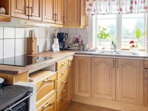a kitchen with wooden cabinets and a sink and a window at Holiday home Lekeryd II in Lekeryd