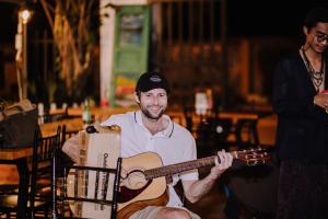 un homme tenant une guitare dans une voiturette dans l'établissement Republic Hostel Cat Ba, à Cat Ba