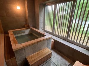 eine Badewanne in einem Zimmer mit Fenster in der Unterkunft Kuriya Suizan in Jozankei