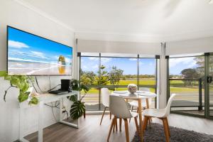 a dining room with a table and chairs and a tv at Driftwood Townhouse - Waterfront-Central Location in Lakes Entrance