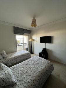Luxueux appartement à la Marina d’agadir في أغادير: غرفه فندقيه سريرين وتلفزيون