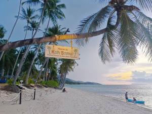 un panneau sur une plage avec des palmiers et l'océan dans l'établissement Baan Tropicana, à Mae Nam Beach