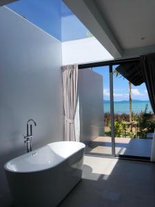 a bathroom with a tub and a view of the ocean at Little Moon Villa in Ko Mak