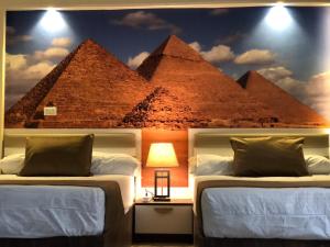 sypialnia z dwoma łóżkami i malowidłem piramid w obiekcie Matto Pyramids Inn w Kairze